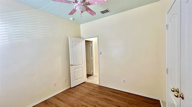 an empty room with wooden floor closet and windows