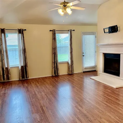 a view of an empty room with wooden floor and a fireplace