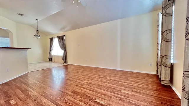 a view of empty room with wooden floor and fan