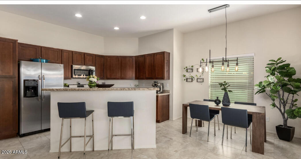 3113 East Danbury Road, Unit 22 Phoenix, AZ 85032 - Photo 3 of 17 a kitchen with stainless steel appliances kitchen island granite countertop a refrigerator a stove a sink dishwasher and a dining table with chair