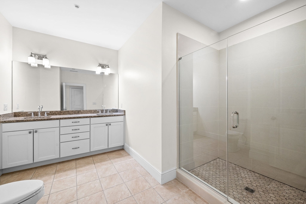 33 Intrepid Circle, Unit 405 Marblehead, MA 01945 - Photo 17 of 31 a spacious bathroom with a granite countertop sink a mirror and a shower