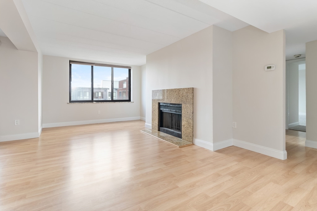 85 Brainerd Road, Unit 507 Boston, MA 02134 - Photo 8 of 23 an empty room with windows a fireplace and wooden floor