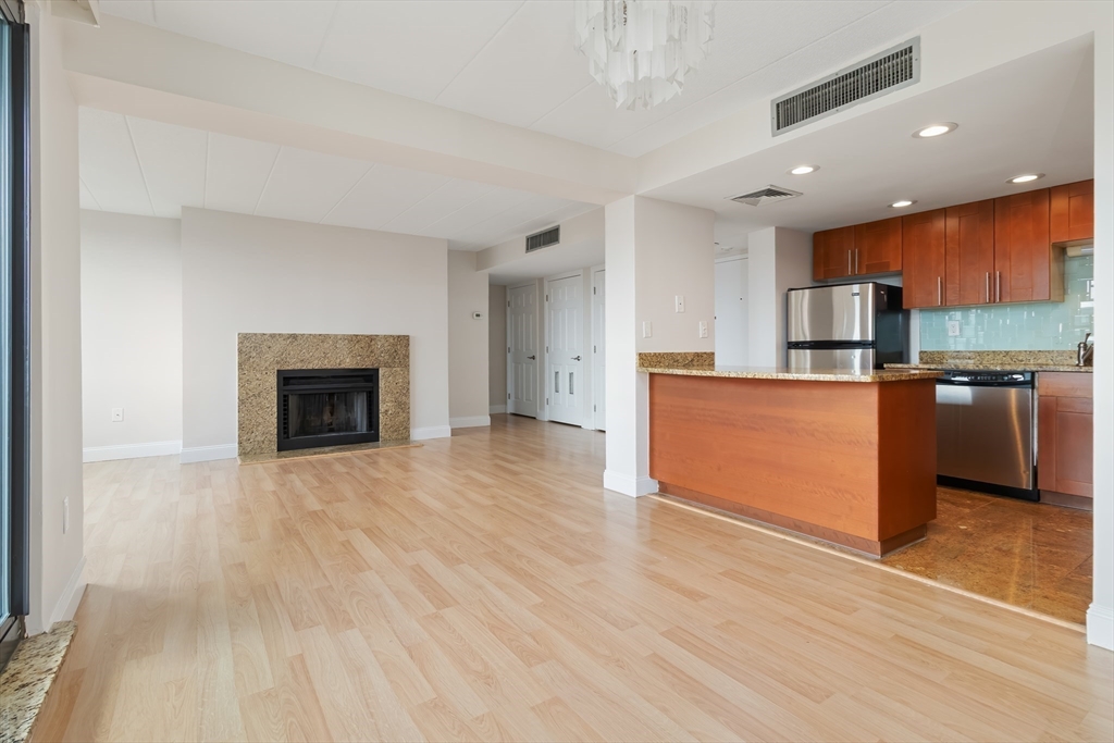 85 Brainerd Road, Unit 507 Boston, MA 02134 - Photo 9 of 23 an empty room with wooden floor and a fireplace