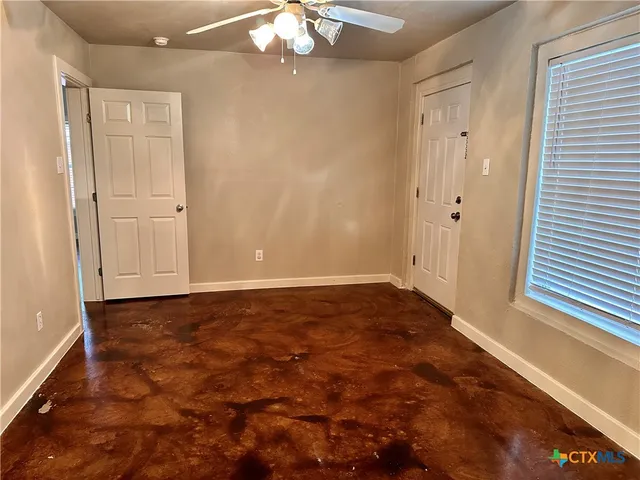 a view of an empty room and chandelier fan