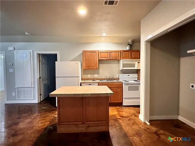 a kitchen with kitchen island a sink appliances and cabinets