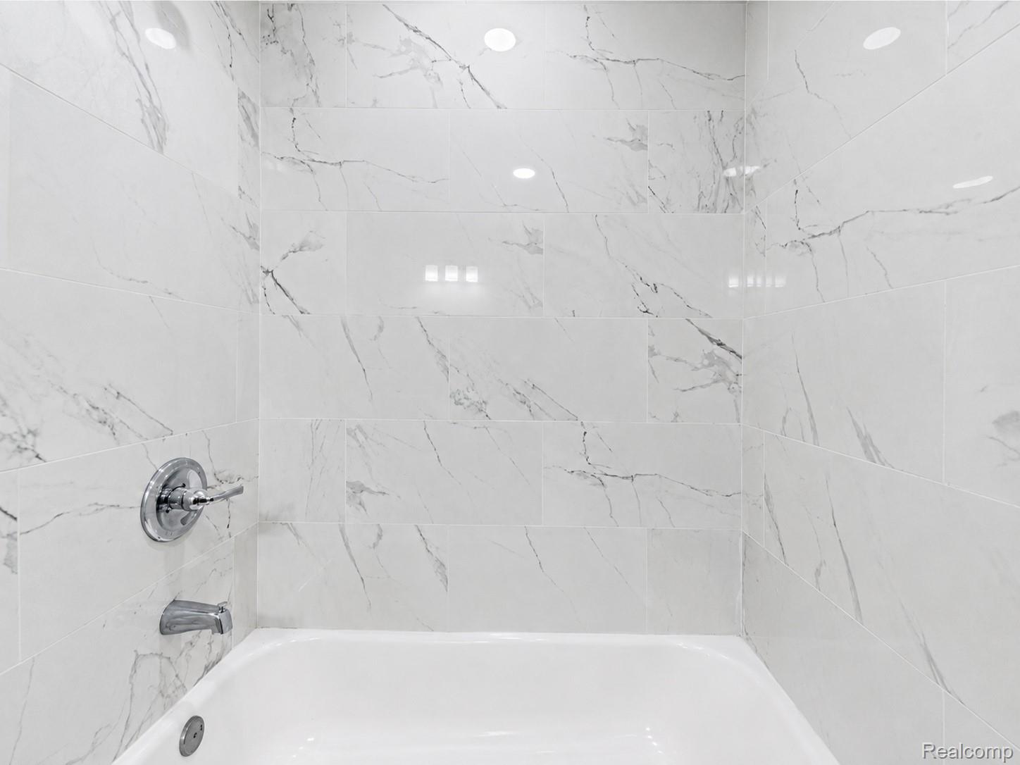 9175 Devonshire Road Detroit, MI 48224 - Photo 12 of 23 Bathtub enclosure featuring large format tile with gray veining, a chrome faucet, and a chrome tub spout