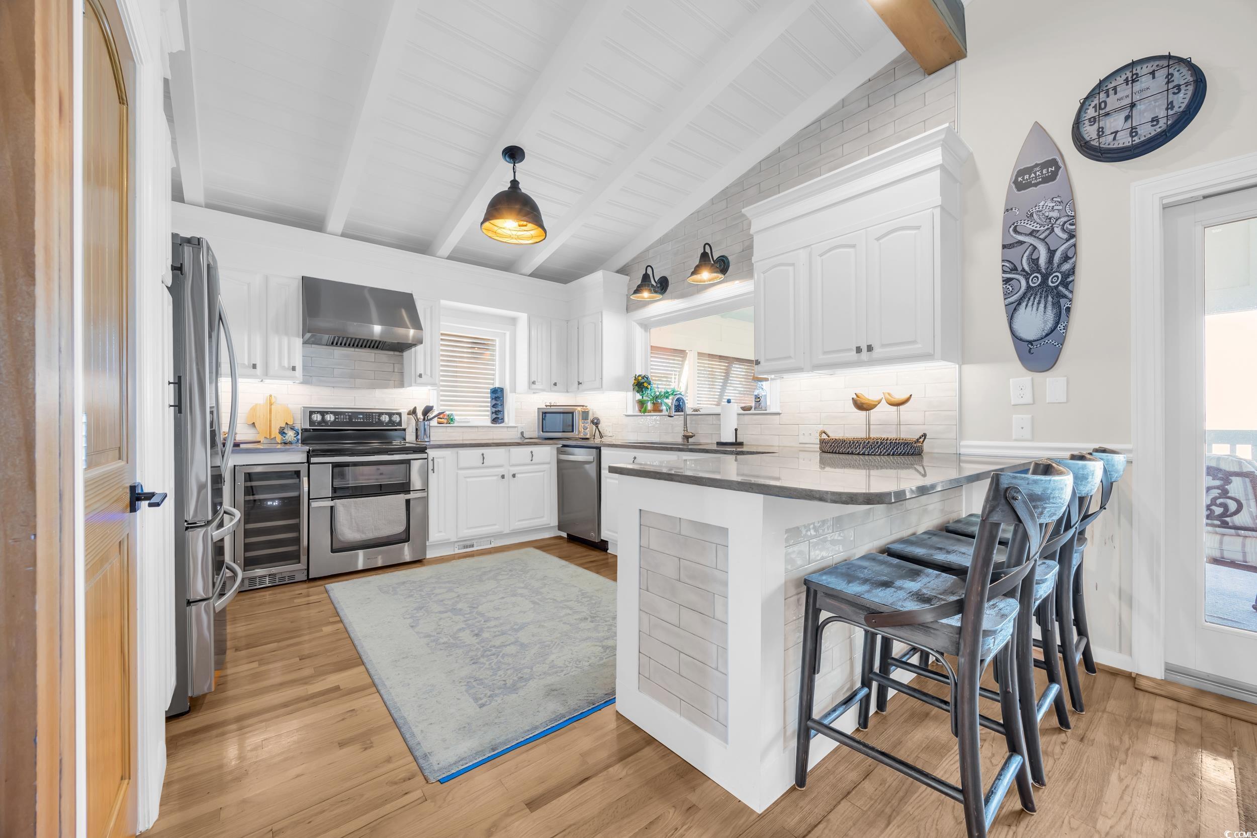 1332 South Waccamaw Drive Murrells Inlet, SC 29576 - Photo 29 of 39 Kitchen with decorative backsplash, dark stone countertops, beverage cooler, and white cabinetry