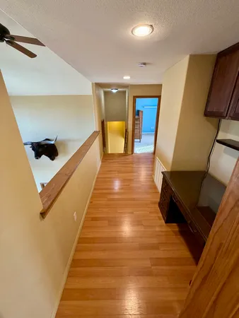 a view of a hallway with wooden floor and staircase