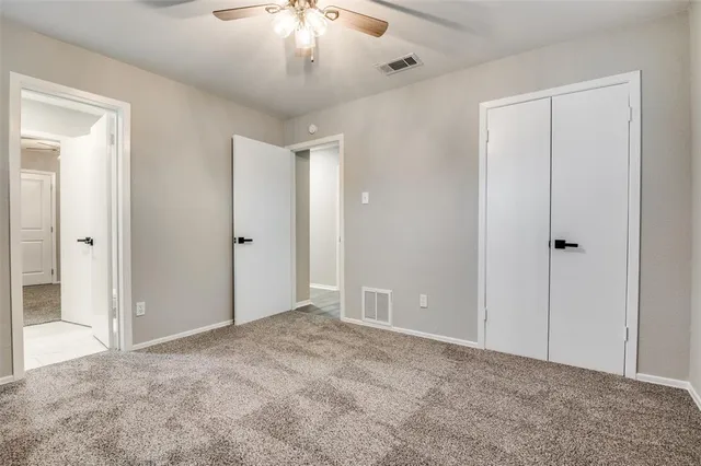 a view of an empty room and chandelier fan
