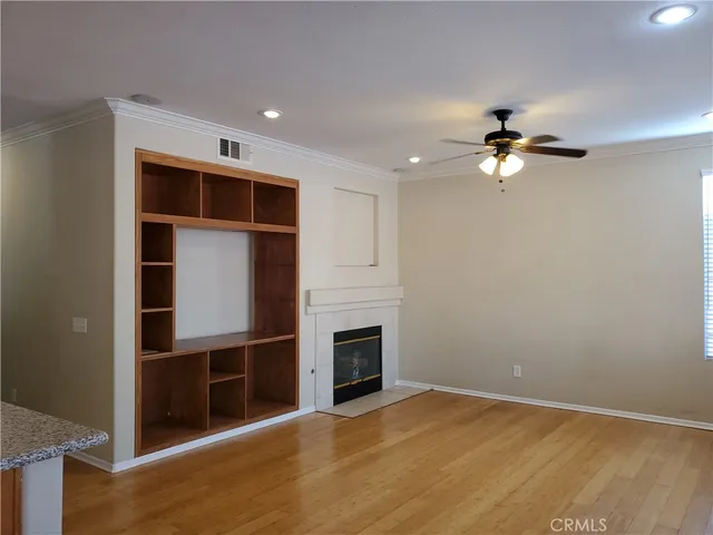 a view of an empty room with a ceiling fan and kitchen view