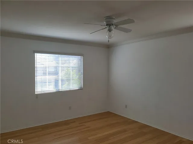 an empty room with wooden floor fan and windows