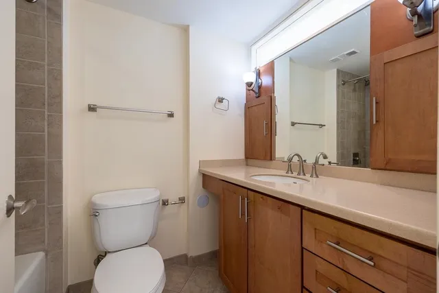 a bathroom with a granite countertop toilet sink and mirror