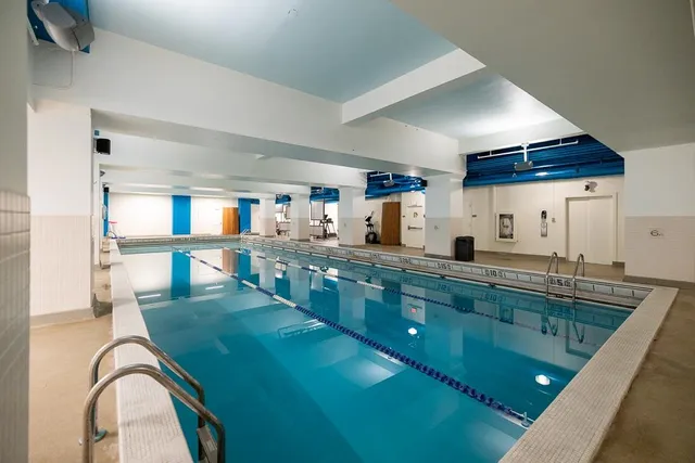 a kitchen with stainless steel appliances granite countertop a sink a stove top oven a dining table and chairs with wooden floor