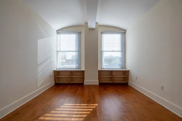 an empty room with wooden floor and windows