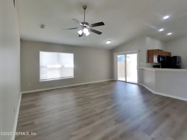 a view of an empty room with a window and wooden floor