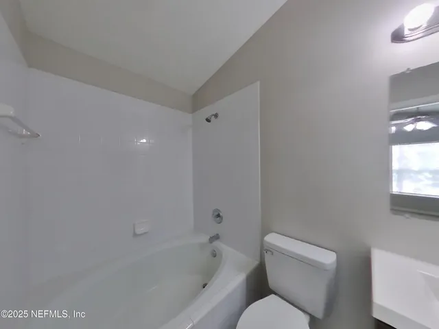 a white toilet sitting next to a bath tub