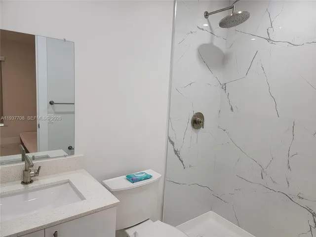 a white toilet sitting next to a bathroom sink and vanity