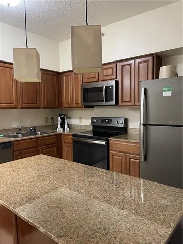 a kitchen with granite countertop a refrigerator and a stove top oven