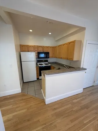 a kitchen with a sink a stove cabinets and wooden floor