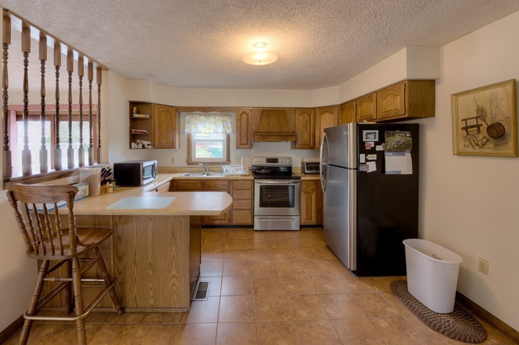 23 Riverside Street Three Rivers, MA 01080 - Photo 4 of 33 a kitchen with stainless steel appliances granite countertop a refrigerator a stove a sink a dining table and chairs
