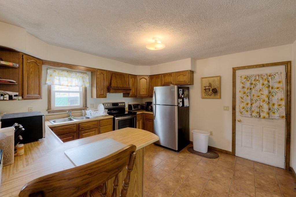 23 Riverside Street Three Rivers, MA 01080 - Photo 6 of 33 a kitchen with stainless steel appliances granite countertop a refrigerator a stove a sink a dining table and chairs with wooden floor