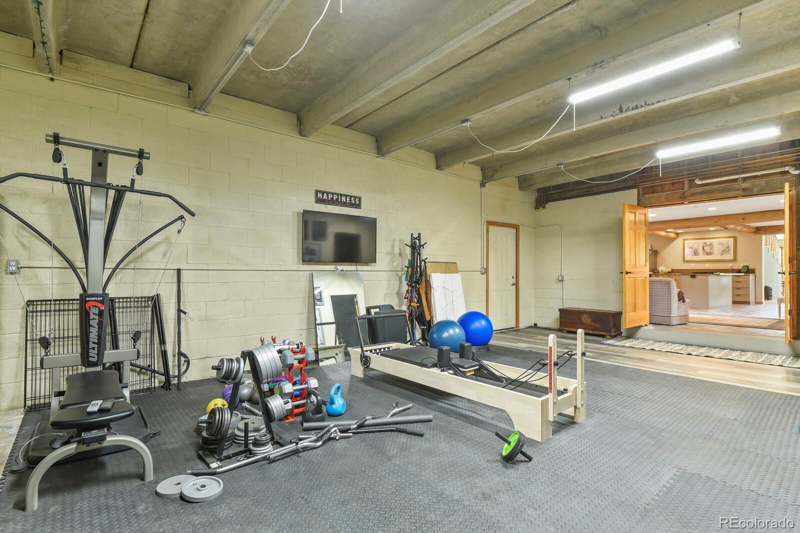 417 Witter Gulch Road Evergreen, CO 80439 - Photo 24 of 50 a living room with furniture gym equipment and a fireplace