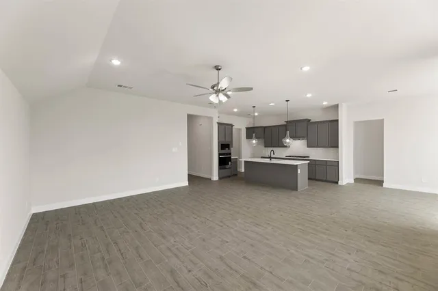 a view of a kitchen with kitchen island a sink wooden floor and a refrigerator