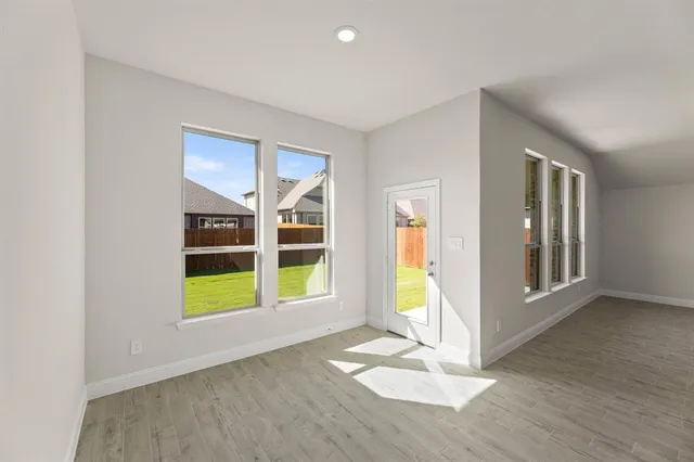 a view of an empty room with a window and wooden floor