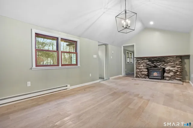 a view of empty room with wooden floor and kitchen