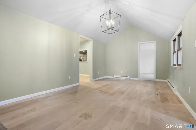 a view of empty room with wooden floor and chandelier
