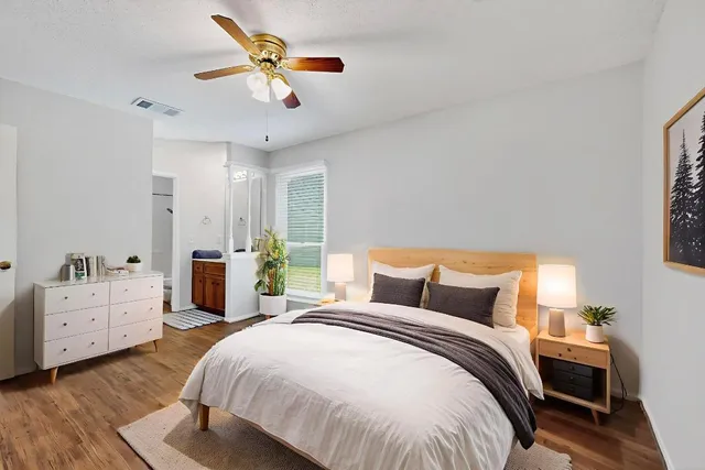 an empty room with wooden floor fan and windows