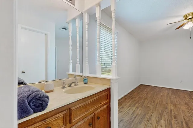 an empty room with wooden floor and a ceiling fan