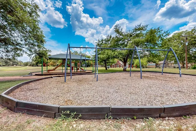 a view of a backyard with large trees and wooden fence