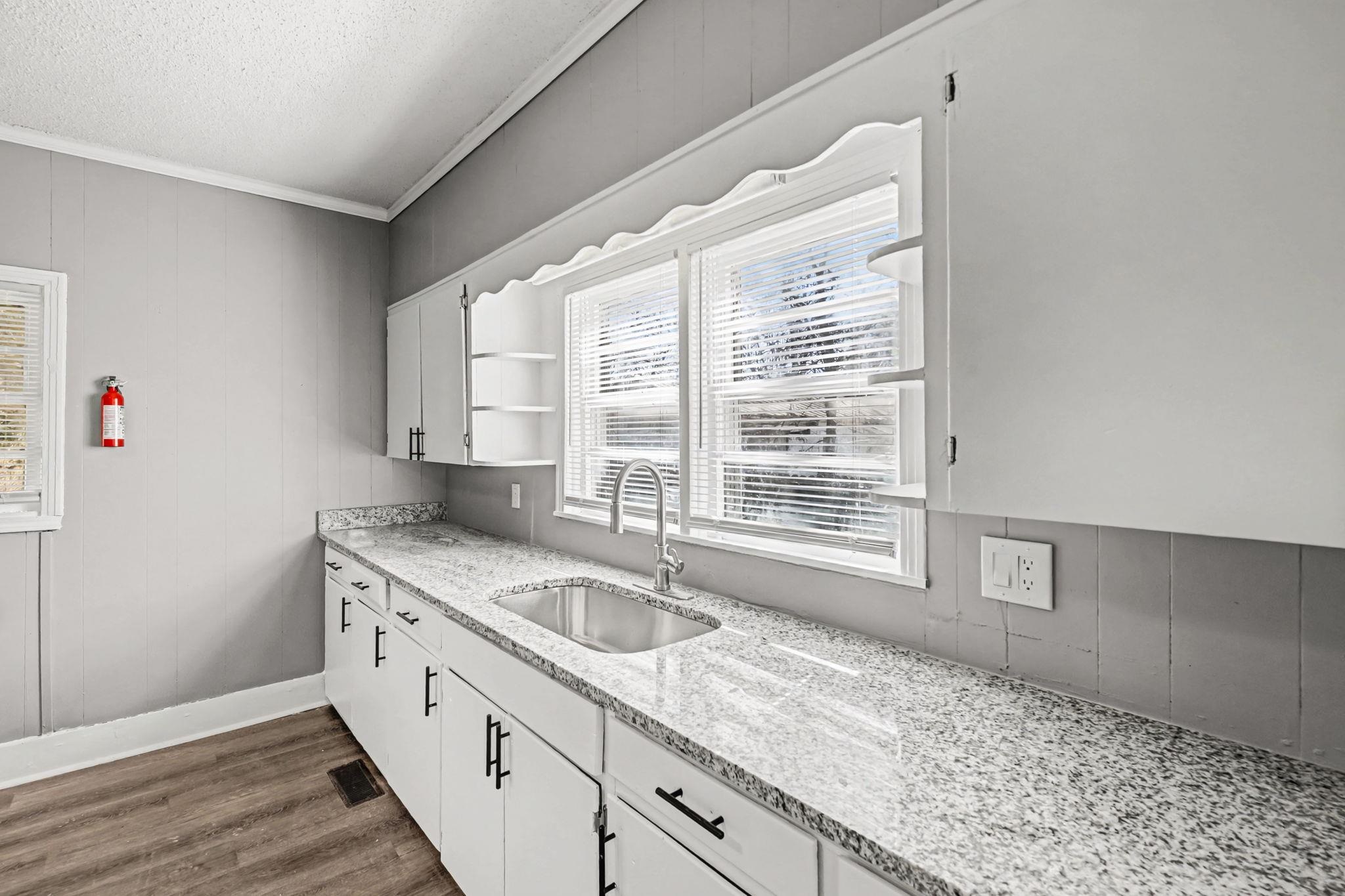 320 North High Street Covington, TN 38019 - Photo 11 of 32 a kitchen with granite countertop a sink stove and cabinets