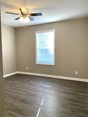 a view of an empty room with window and wooden floor