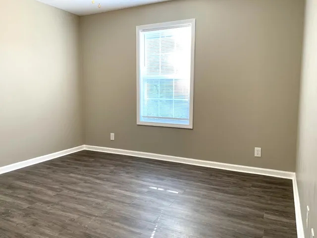 an empty room with wooden floor and a window