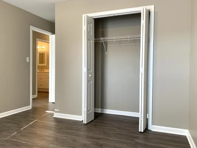 a view of an empty room with wooden floor & closet