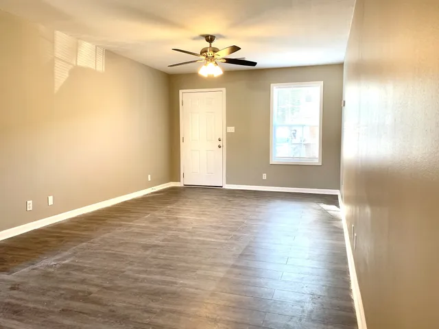 an empty room with wooden floor and windows