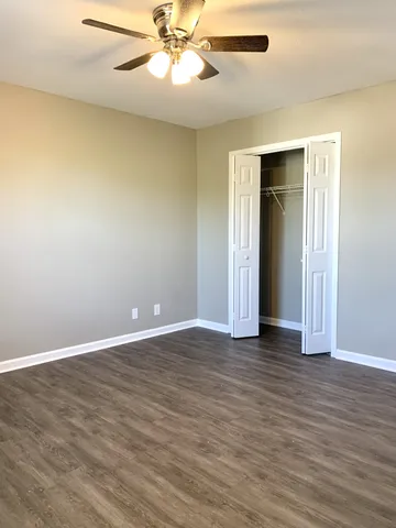 an empty room with wooden floor closet and windows