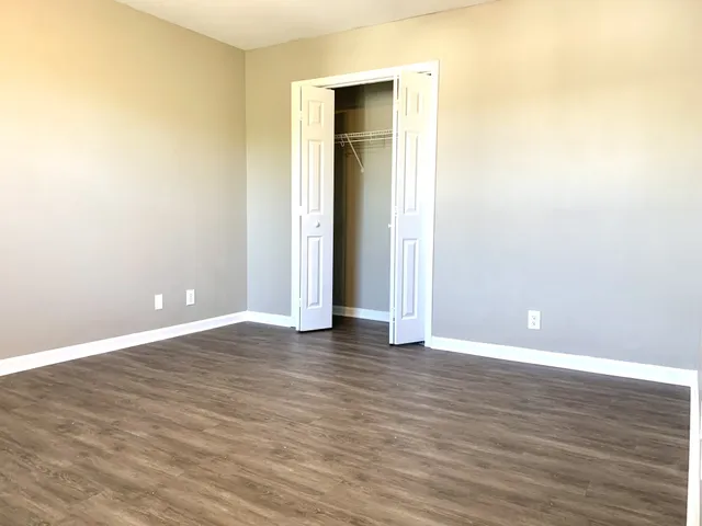 a view of an empty room with wooden floor and closet