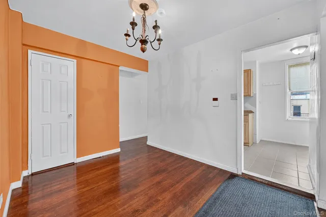 an empty room with wooden floor and hallway