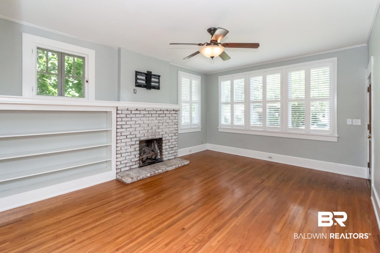 10 Macy Place Mobile, AL 36604 - Photo 4 of 43 Unfurnished living room featuring ceiling fan, wood finished floors, a fireplace, ornamental molding, and built in features