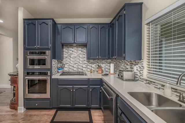 a kitchen with stainless steel appliances kitchen island granite countertop a stove refrigerator and cabinets