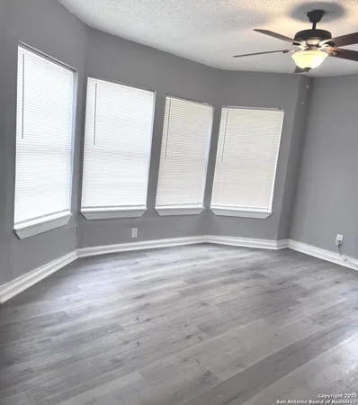 a view of an empty room with a window and wooden floor