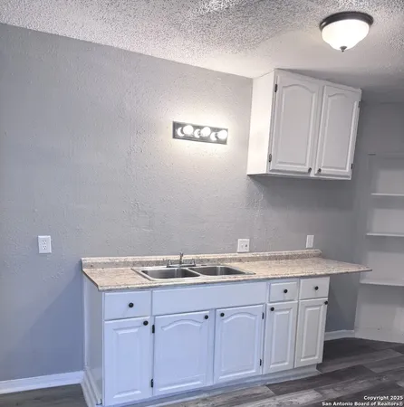 a sink with granite countertop white cabinets