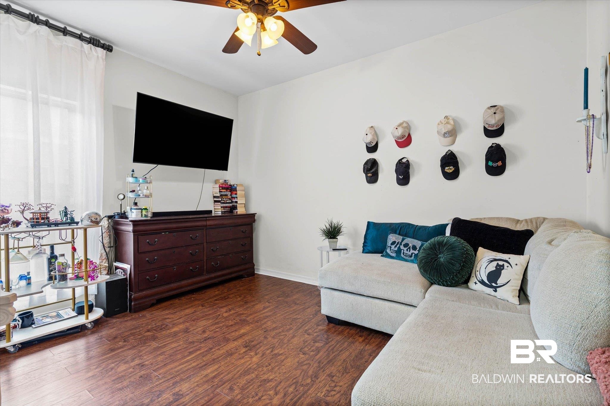 800 Galoway Avenue Mobile, AL 36609 - Photo 14 of 22 Living area featuring wood-finish flooring, white walls, a ceiling fan with integrated lighting, and a large window with sheer white curtains