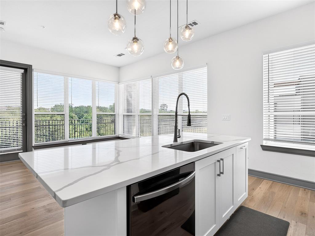 Kitchen island featuring a single-basin sink, matte black faucet, and white countertop with veining