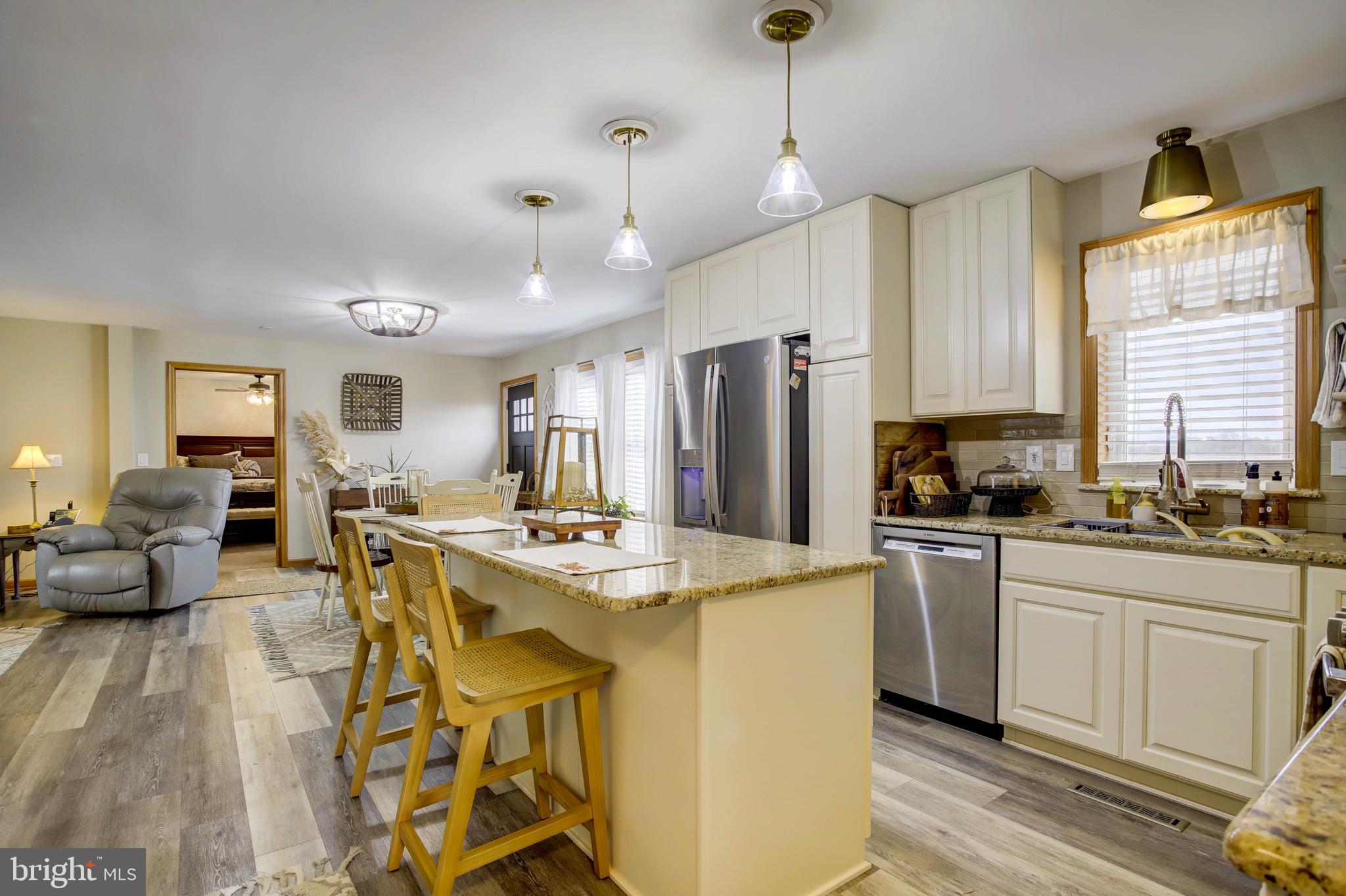 5520 Indiantown Road Rhodesdale, MD 21659 - Photo 14 of 51 a kitchen with stainless steel appliances granite countertop a stove a refrigerator a kitchen island white cabinets and couches with wooden floor
