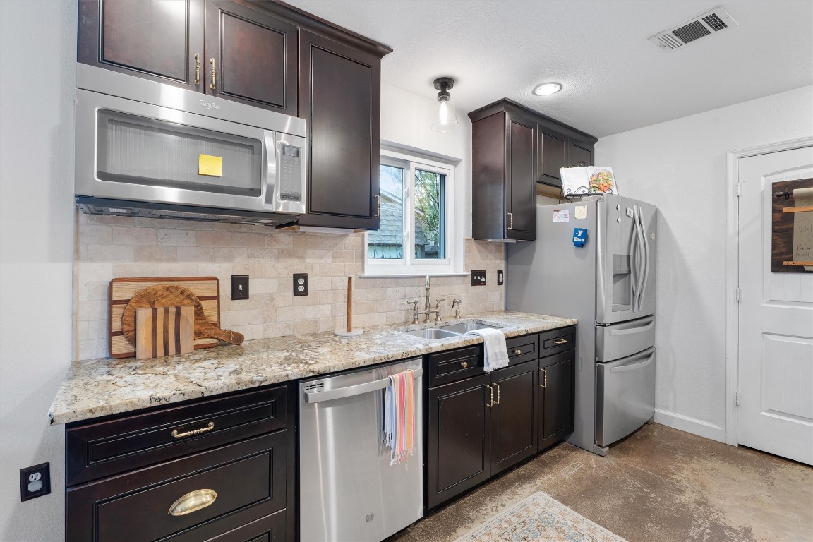 1808 Chincoteague Way Round Rock, TX 78681 - Photo 12 of 40 a kitchen with stainless steel appliances granite countertop a sink stove and refrigerator