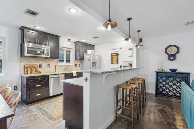 a large kitchen with stainless steel appliances granite countertop a sink stove and refrigerator
